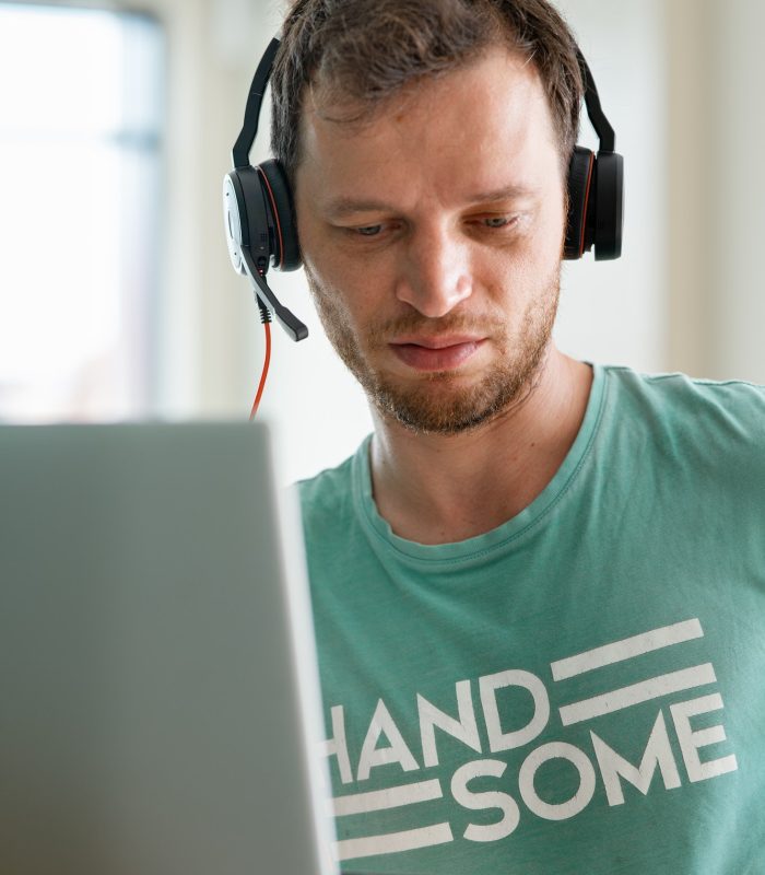 young-programmer-works-from-home-using-laptop-and-headphones.jpg